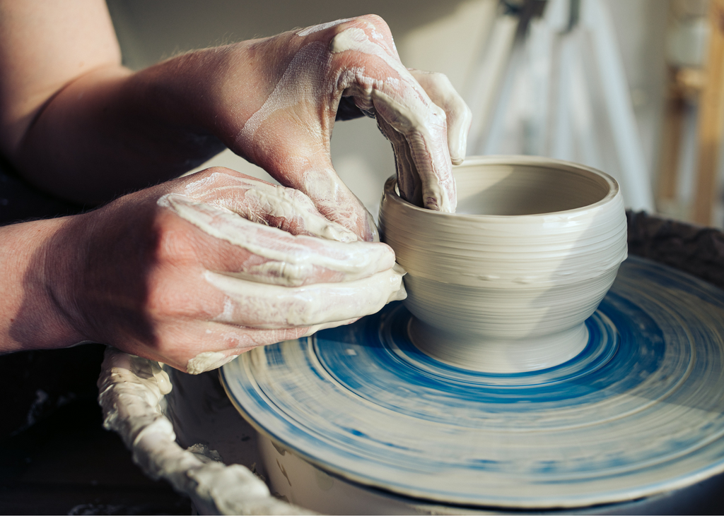 A potter works on a small bowl on a potter's wheel.